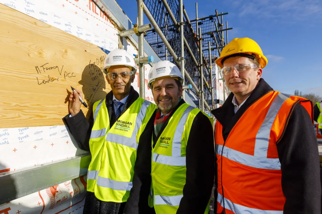 Cllr Farooq, Mayor Dr Johnson and Prof Renton sign one of the roof panels at the topping out ceremony.