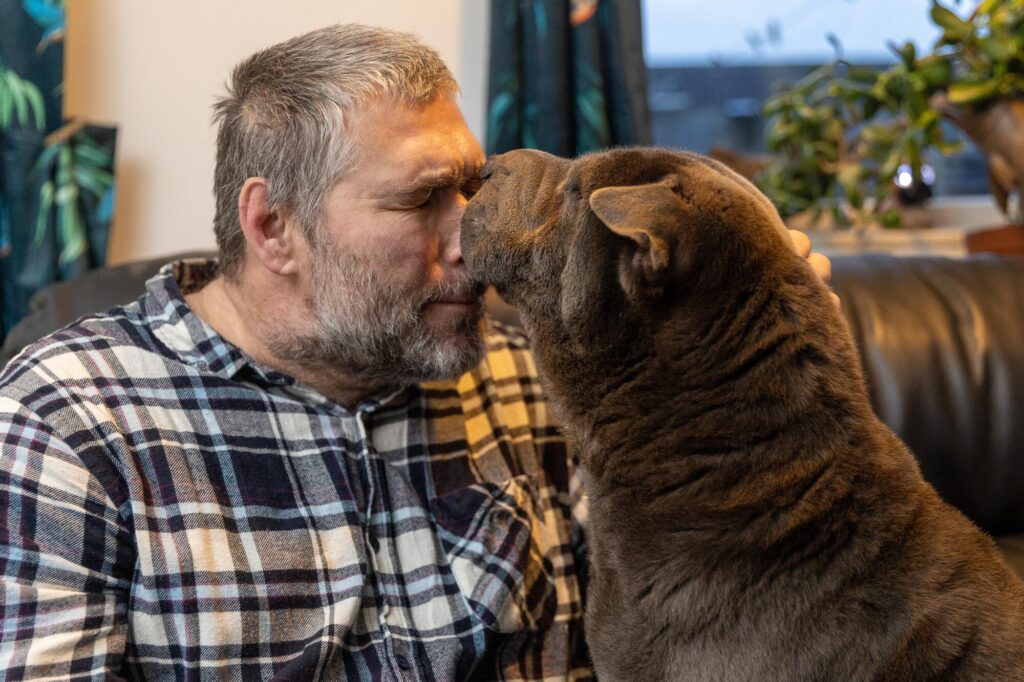 John Goude intervened as a dog attacked a teenager with many bystanders agreeing that John saved the teenager’s life. The dog had already attacked the mother of the teenager. March Monday 04 November 2024. Pictured relaxing at home with his own dog, Lilly by Terry Harris