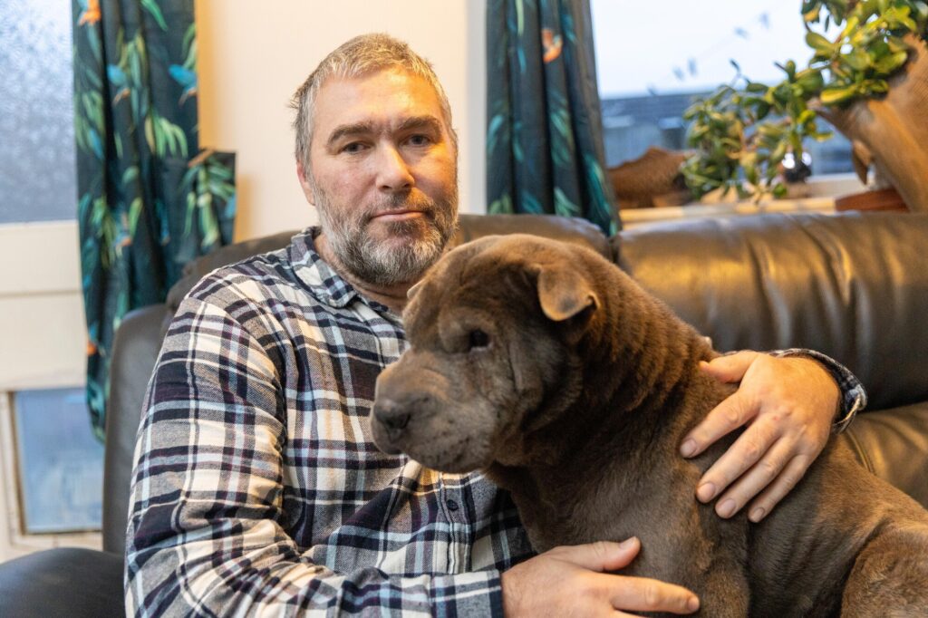 John Goude intervened as a dog attacked a teenager with many bystanders agreeing that John saved the teenager’s life. The dog had already attacked the mother of the teenager. March Monday 04 November 2024. Pictured relaxing at home with his own dog, Lily by Terry Harris