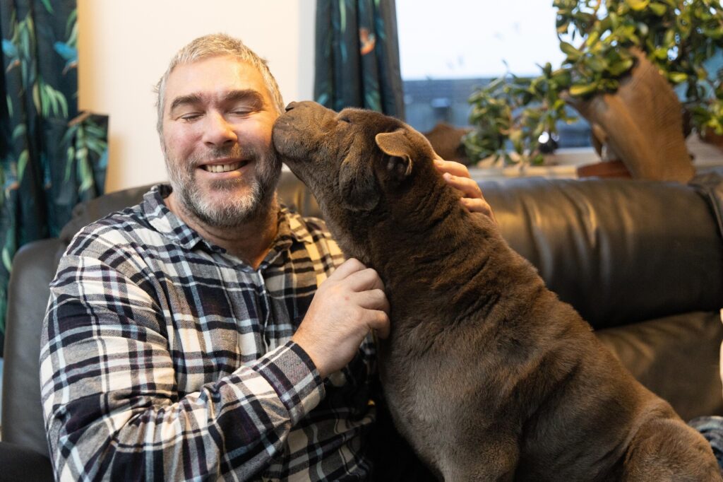 John Goude intervened as a dog attacked a teenager with many bystanders agreeing that John saved the teenager’s life. The dog had already attacked the mother of the teenager. March Monday 04 November 2024. Pictured relaxing at home with his own dog, Lily by Terry Harris